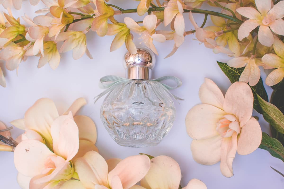 An ornate crystal flacon surrounded by pale orange blossom