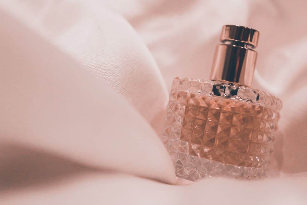 A faceted rose-tinted flacon nestled in soft silk