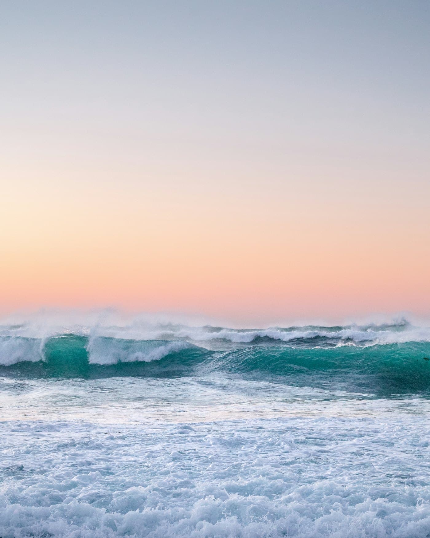 Pastel surf breaking under a soft dawn sky
