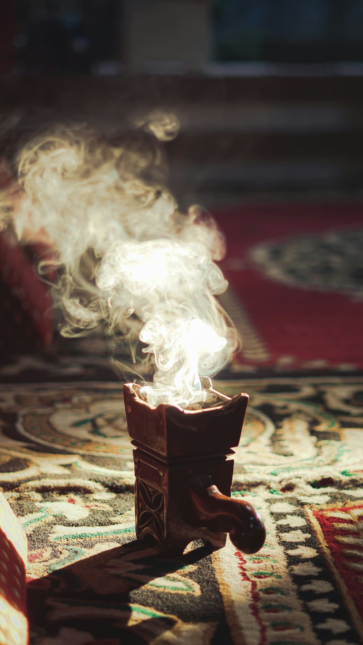 Incense smoke curling from a carved wooden burner